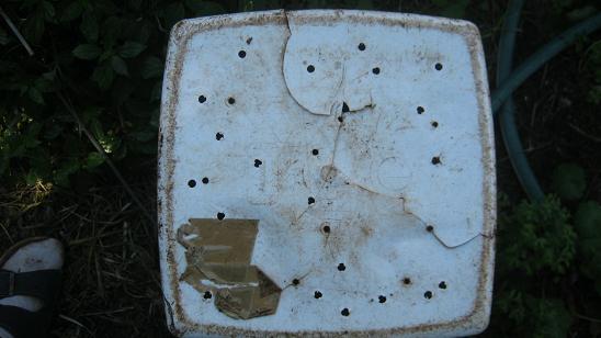 The bottom of a budget worm bin with drainage holes.